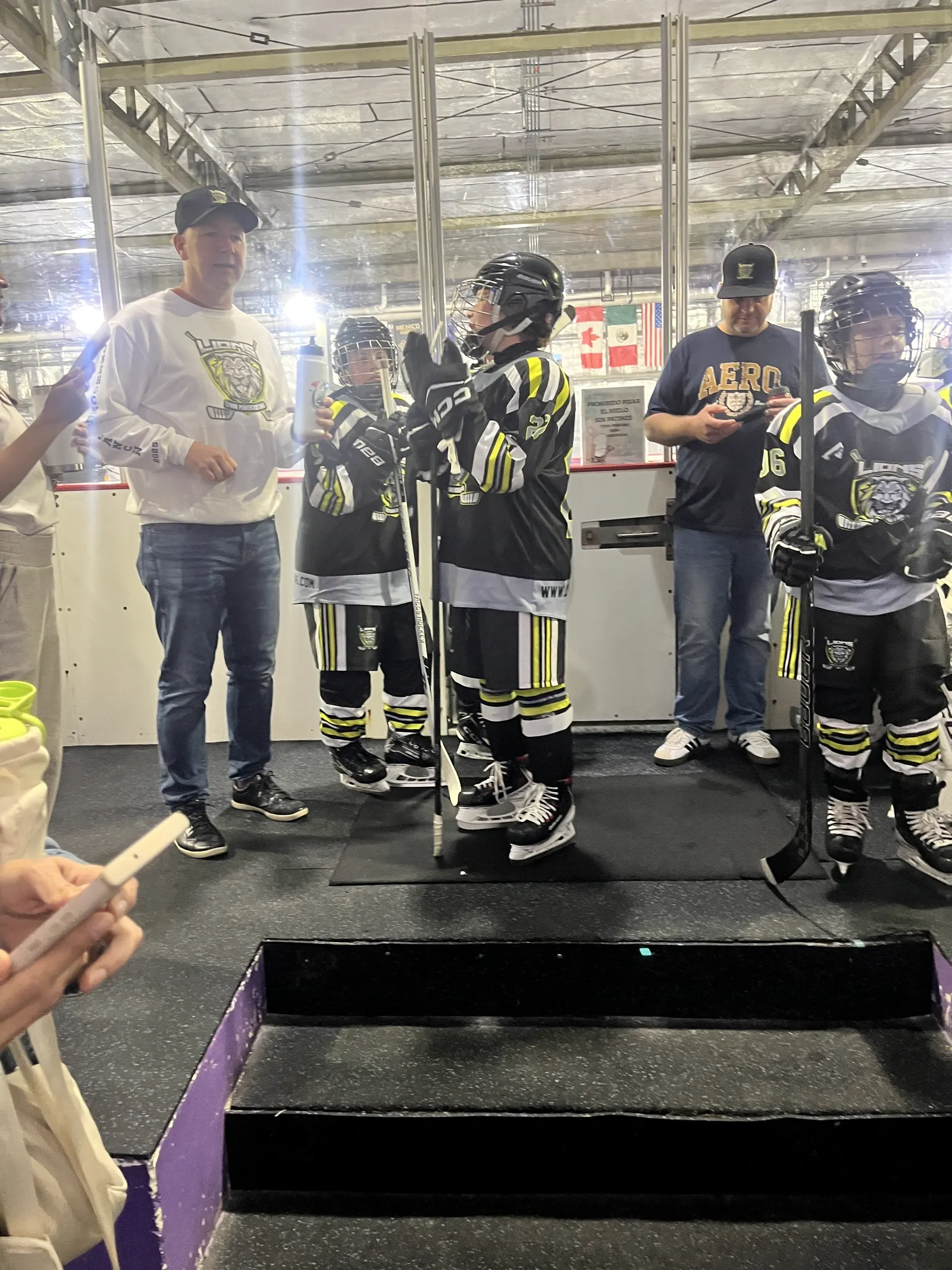 Young players standing on the podium beside the OneHockey Cup in Cancún