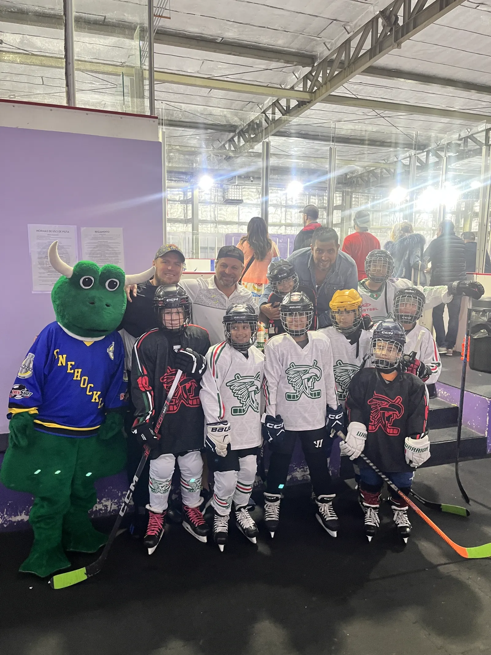 A youth team posing with Freddie the mascot in the hallway of the Cancún rink, November 2025